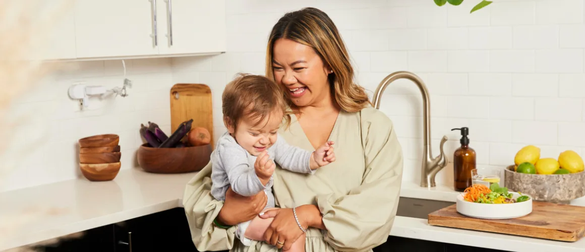Woman with smiling baby in kitchen.