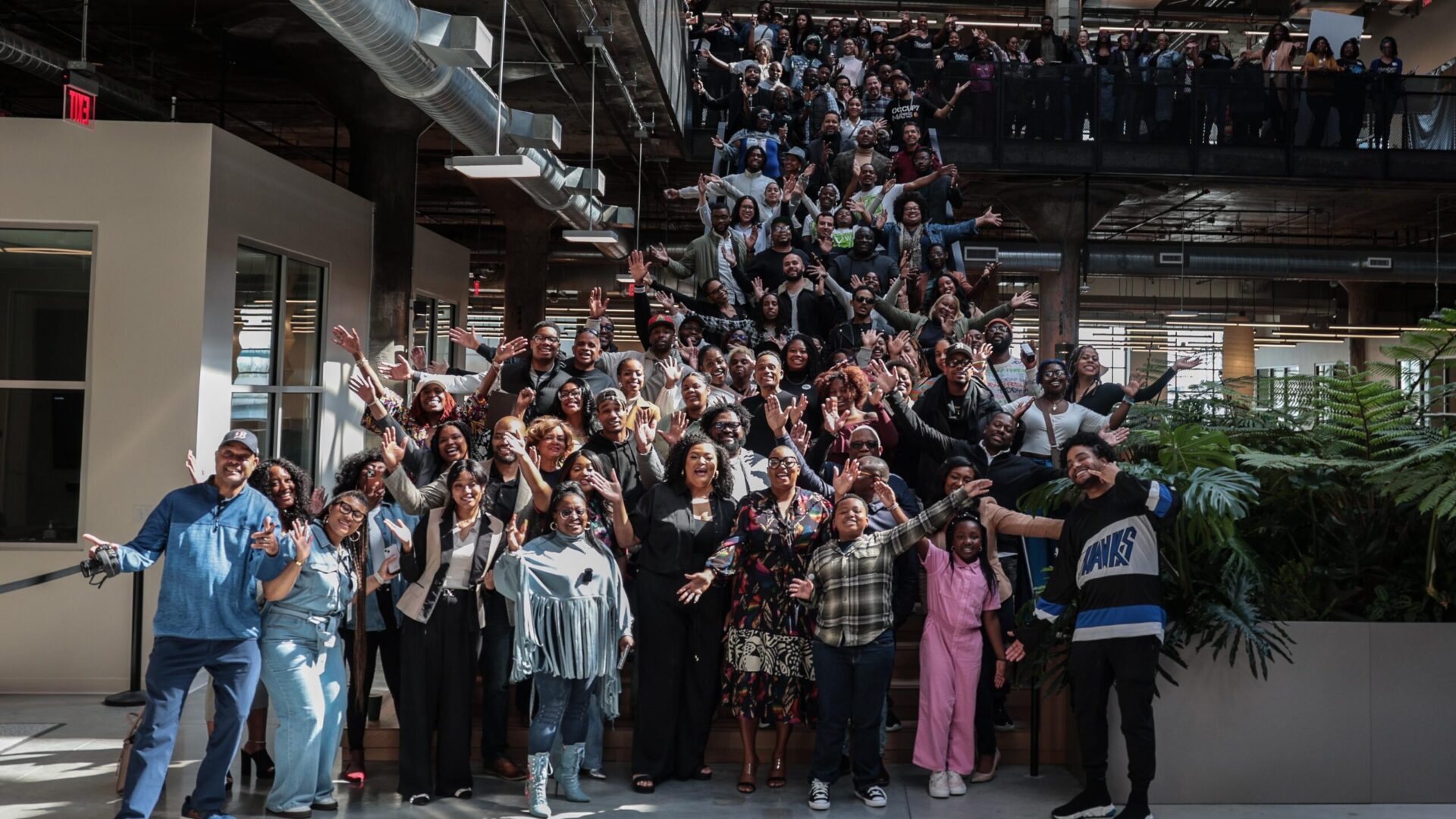 A photo of participants at Black Tech Saturdays. Around fifty people posing for a photo on a set of stairs in an atrium.