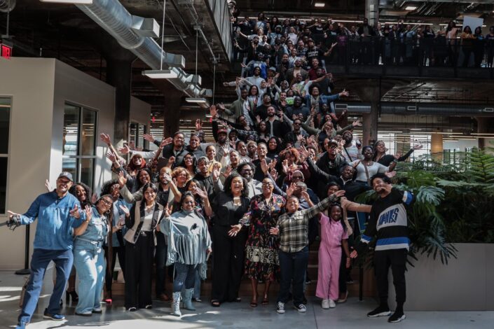 A photo of participants at Black Tech Saturdays. Around fifty people posing for a photo on a set of stairs in an atrium.