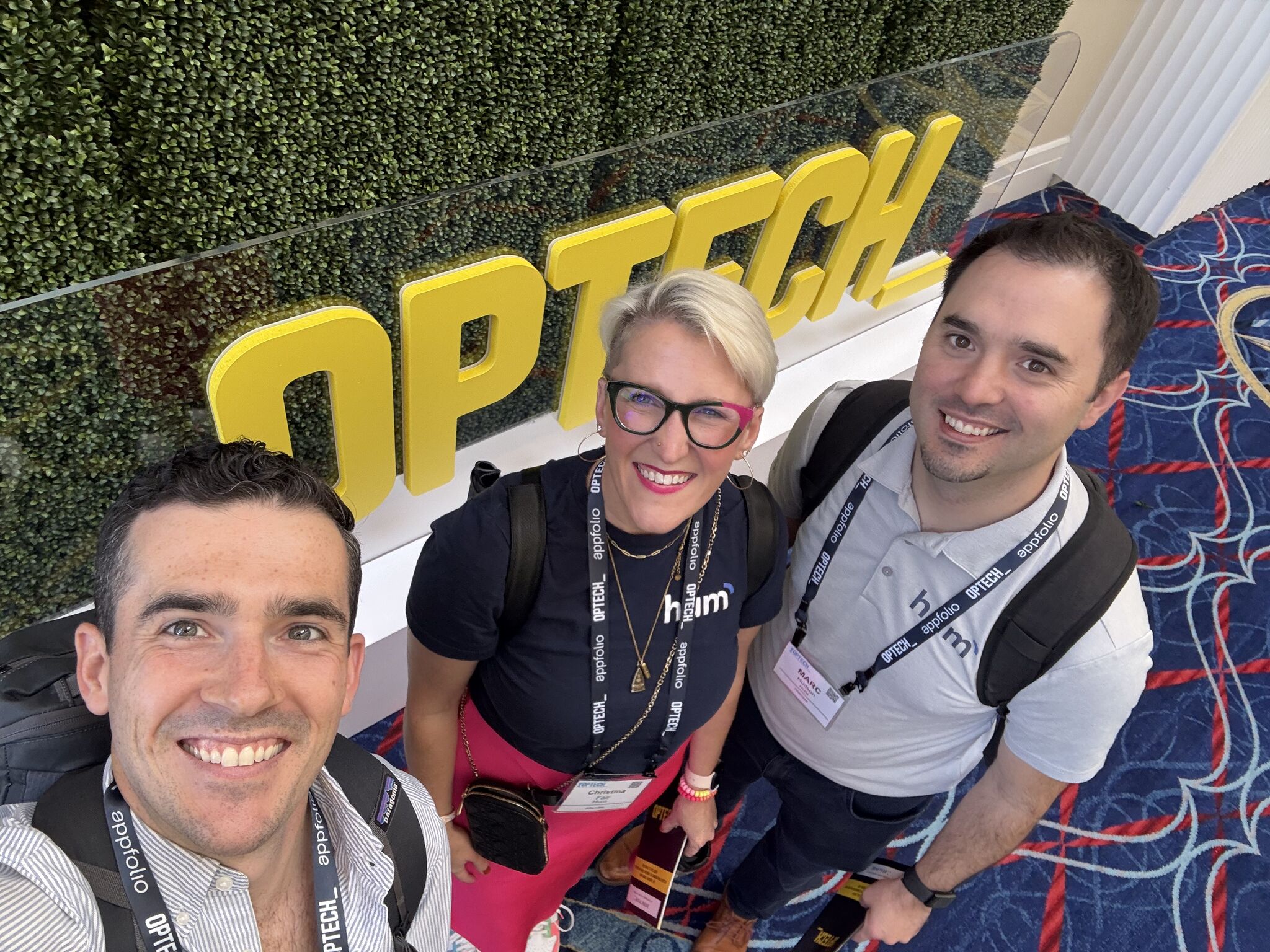 A selfie of the co-founders of Hum in front of a sign saying optech. 