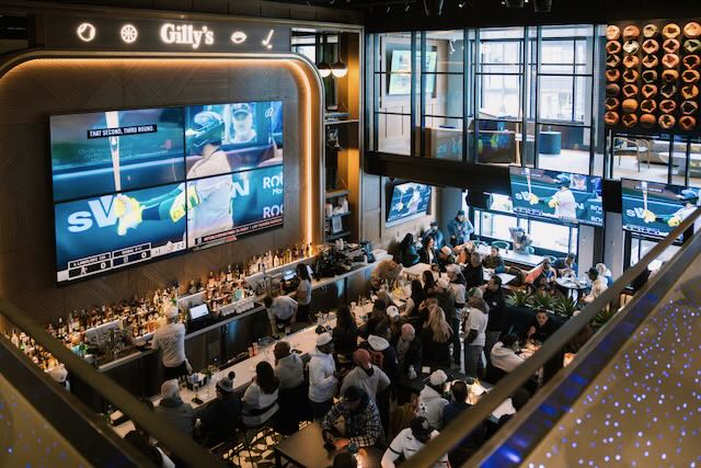Picture of Gilly's Clubhouse with people eating and drinking and the large TV showing baseball. 